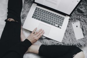 woman casually writing a blog on her bed